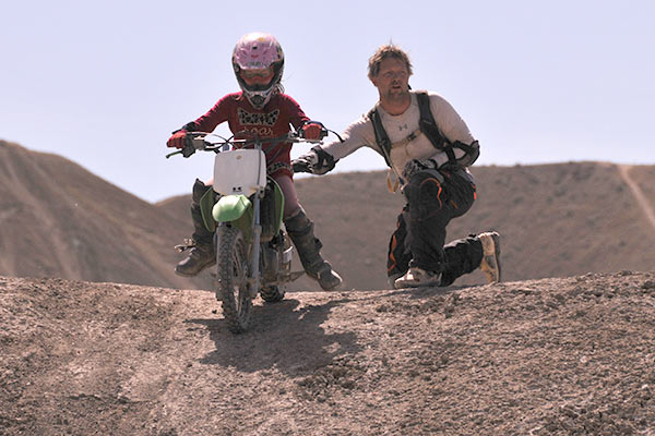 Father helps daughter to ride a dirtbike